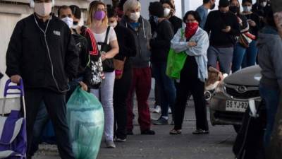 Un grupo de personas espera para comprar alimentos en un supermercado de Santiago, Chile./AFP.