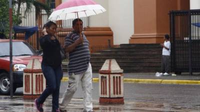 Dos personas se protegen de la lluvia en el centro.