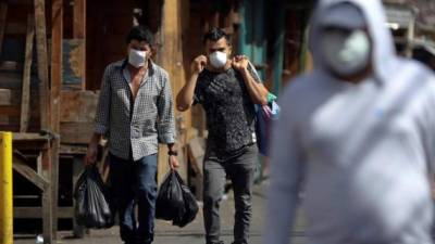 Dos hombres regresan de comprar en un mercado el pasado lunes, en la ciudad de Comayagüela (Honduras). EFE/Gustavo Amador