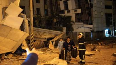 Two guests are escorted by rescue workers from the damaged Marshal Hotel in Hualien, eastern Taiwan early February 7, 2018, after a strong earthquake struck the island. A hotel on the east coast of Taiwan has collapsed after a 6.4-magnitude earthquake, the government said. / AFP PHOTO / YANG JEN-FU / Taiwan OUT