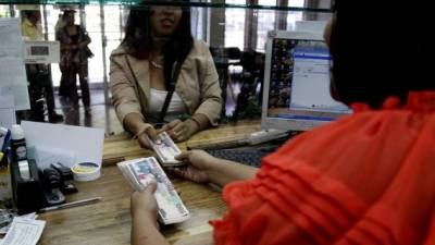 Una joven reclama remesas en una institución bancaria de La Ceiba.