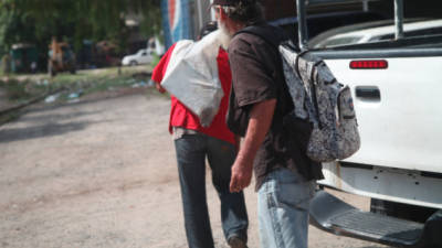 Uno de los hombres se echa el saco con la batería a la espalda.