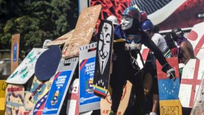 Manifestantes venezolanos se enfrentan a agentes antimotines durante una protesta en Caracas.AFP.