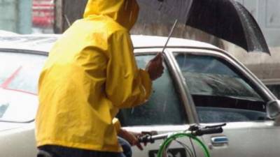 Un joven en bicicleta se protege de la lluvia.