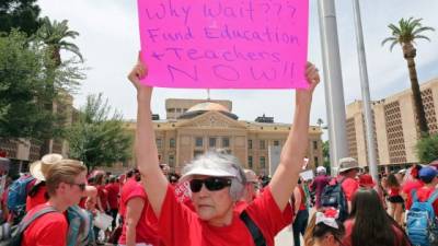 Una anciana de setenta y tres años sosteniendo un cartel en apoyo a los maestros.
