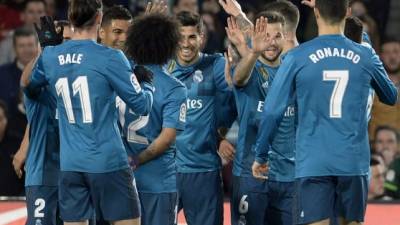 Real Madrid's Spanish midfielder Marco Asensio (C) celebrates scoring a goal with teammates during the Spanish league football match Real Betis vs Real Madrid at the Benito Villamarin stadium in Sevilla on February 18, 2018. / AFP PHOTO / Cristina Quicler