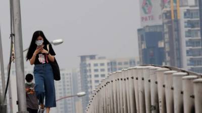 Una muchacha lleva una mascarilla mientras cruza un paso elevado de Bangkok (Tailandia). EFE