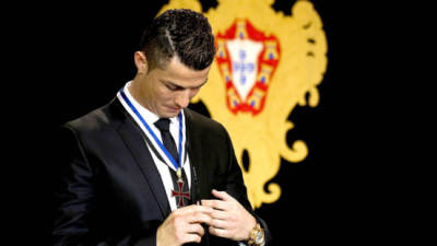 Cristiano Ronaldo mira su condecoración tras ser nombrado 'Gran Oficial'.