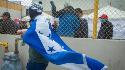 Un hombre envuelto en una bandera nacional hondureña camina hacia un refugio para migrantes centroamericanos en Piedras Negras, estado de Coahuila. AFP