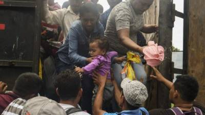 Honduran migrants taking part in a caravan heading to the US, aboard a truck, arrive at the border crossing point with Mexico, in Ciudad Tecun Uman, 257 kilometers south of Guatemala City, on October 19, 2018. - Honduran migrants who have made their way through Central America were gathering at Guatemala's northern border with Mexico on Friday, despite President Donald Trump's threat to deploy the military to stop them entering the United States. (Photo by ORLANDO SIERRA / AFP)