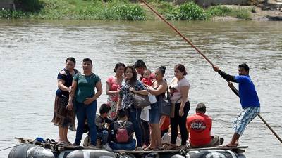 Un grupo de mujeres y niños cruzan un río entre Guatemala y México. AFP