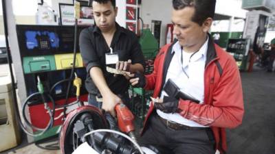 Un motociclista paga a un bombero de una gasolinera en la capital.