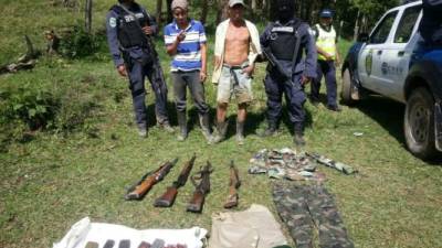 Los dos detenidos con las armas que les fueron decomisadas por las autoridades.