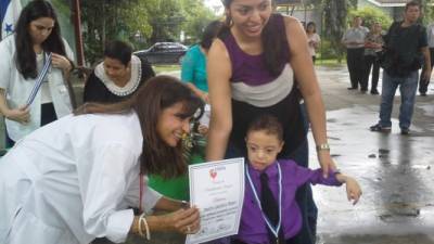 La directora de la Teletón en San Pedro Sula entrega el certificado a un menor que la logrado su meta en la fundación.