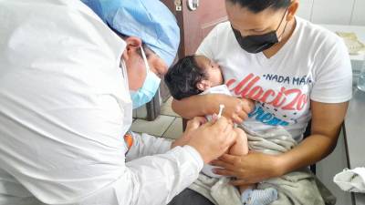 Padres de familia y sus hijos en un centro de vacunación.