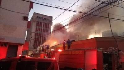 Bomberos en labores de enfriamiento en Tegucigalpa, capital de Honduras, después de que las llamas consumieran cinco negocios.