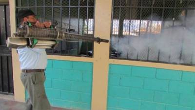 Un hombre fumiga una escuela de la capital hondureña.
