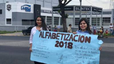 Dos jóvenes conmemoran el Día Internacional de la Alfabetización con una pancarta durante un desfile desarrollado en San Pedro Sula.