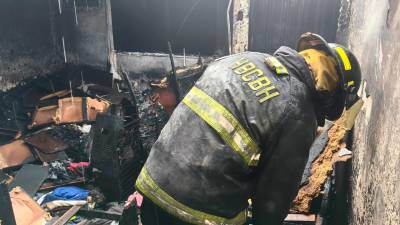 Miembro del Cuerpo de Bomberos inspecciona la vivienda afectada por las llamas.
