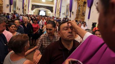 Un sacerdote pone una cruz en la frente de un feligrés en el Miércoles de Ceniza.