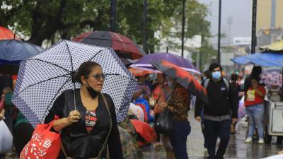 Ciudadanos usan paraguas para cubrir de la lluvia.