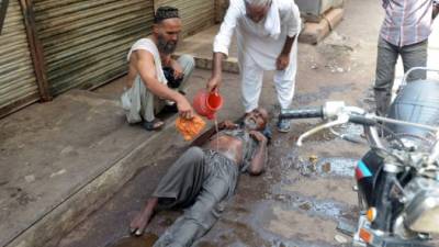 Un grupo de hombres auxilian a un anciano que sufrió un golpe de calor.