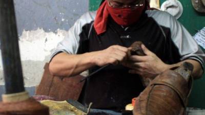 Un zapatero trabaja en uno de los talleres instalados en la zona de los mercados de San Pedro Sula.