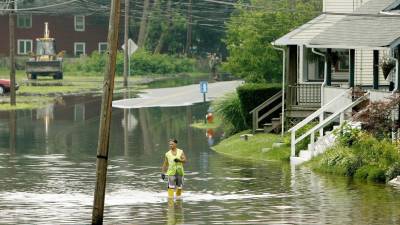 Un trabajador municipal camina por la zona inundada del río Delaware en una calle de Morrisville, en Pensilvania.