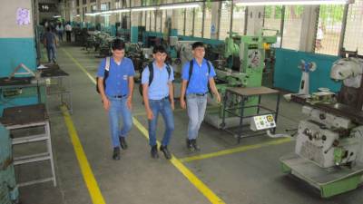 Tres estudiantes del Centro Técnico Hondureño Alemán caminan por el taller de máquinas y herramientas.