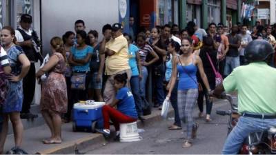Usuarios hacen filas a las afueras de una institución bancaria en San Pedro Sula, Honduras.