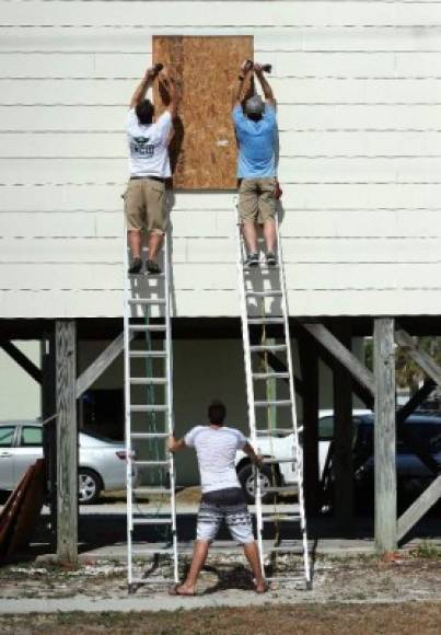 Los residentes que optaron por quedarse en sus casas protegen sus viviendas con planchas de madera y hacen acopio de alimentos y agua.