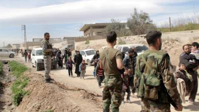 Varios soldados sirios vigilan la evacuación de cientos de civiles que abandonan la zona de Guta Oriental, en la zona rural de Damasco (Siria) el 15 de marzo de 2018. EFE
