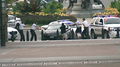 = RESTRICTED TO EDITORIAL USE - MANDATORY CREDIT 'AFP PHOTO / ALHURRA TELEVISION' - NO MARKETING NO ADVERTISING CAMPAIGNS - DISTRIBUTED AS A SERVICE TO CLIENTS  NO ARCHIVE == This framegrab taken courtesy of Alhurra Television, shows police officers with guns drawn approaching a black car on October 3, 2013, near the US Capitol. A volley of shots rang out outside the US Capitol building as police intercepted a suspect Thursday, sending lawmakers and tourists scattering for cover and triggering a massive security operation. Police said a driver had attempted to get past a barricade outside the White House, just over a mile away, and had been pursued across downtown Washington to the building that houses the country's lawmakers. A police car was left badly damaged by what appeared to be a collision on Constitution Avenue, immediately outside the Capitol, and a group of tourists were escorted inside. A woman was taken into custody by police after the shootout. Officials said that there was also a child in the car. AFP PHOTO/ALHURRA TELEVISION