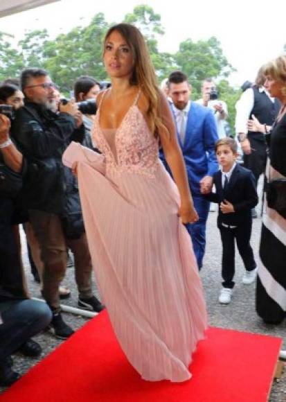 Antonella Roccuzzo, esposa de Messi, sorprendió a todos con un largo vestido escotado rosado y una cartera del mismo color.