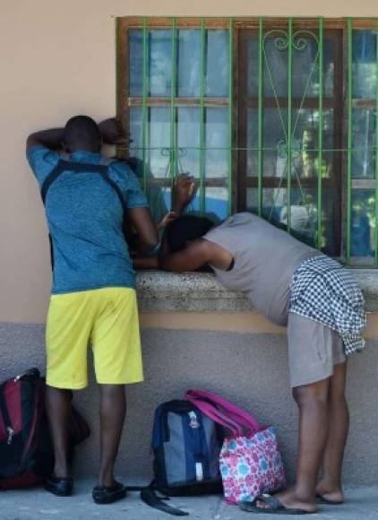 Una pareja de migrantes haitianos descansa afuera de la oficina de migraciones en Choluteca, Honduras.