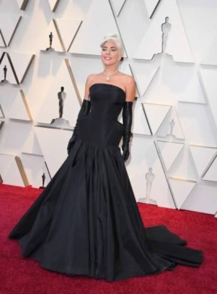 Lady Gaga desfiló por la alfombra roja con un dramático vestido de color negro en corte trompeta firmado por Armani y unos guantes del mismo tono.