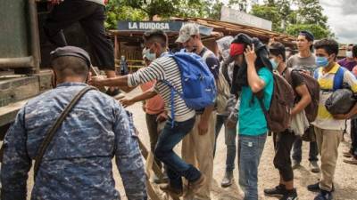 Un grupo de migrantes suben a un camión del Ejército de Guatemala que los regresaría a la frontera entre Honduras y Guatemala, este sábado, en Morales.