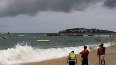 Bañistas observan el oleaje en el puerto de Acapulco.