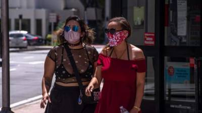 Dos mujeres visten máscaras mientras pasean en Miami Beach, Florida.