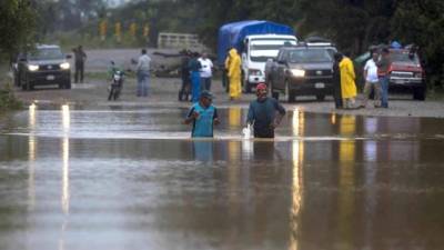 Dos hombres cruzan por un camino inundado en la comunidad Okonwas hoy.