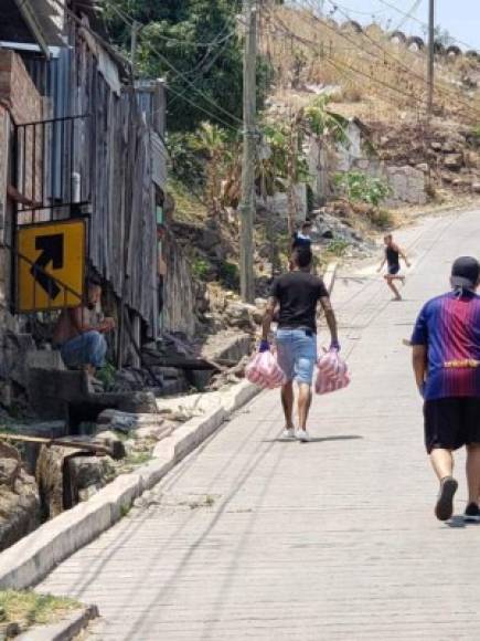 El futbolista del Marathón caminando por las calles en las que se crió para entregar las donaciones.