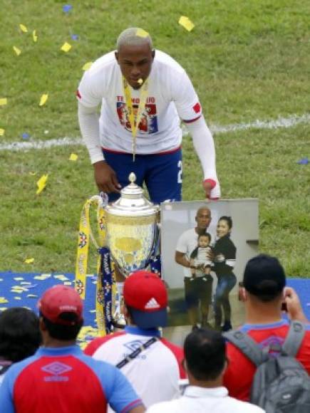 Deiby Flores posando con la Copa y una fotografía de su familia.