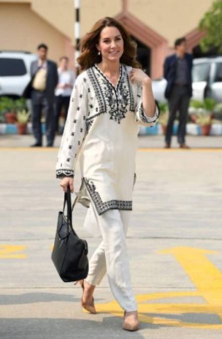 Para abordar el vuelo a casa, Kate combinó una kurta en blanco y negro de la marca paquistaní Élan con tacones J.Crew , pantalones blancos y una bolsa de mano.