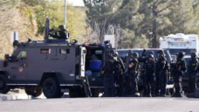 Members of the Phoenix Police Department SWAT team prepare to enter the home of a suspected gunman who opened fire at a Phoenix office building, wounding three people, one of them critically, and setting off a manhunt that led police to surround his house for several hours before they discovered he wasn't there, Wednesday, Jan. 30, 2013, in Phoenix. Authorities believe there was only one shooter, but have not identified him or a possible motive for the shooting. They don't believe the midmorning shooting at the complex was a random act.(AP Photo/Ross D. Franklin)