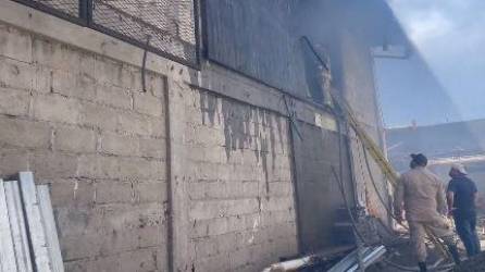 Momento en el que los Bomberos intentan sofocar las llamas del incendio registrado este jueves en una bodega del barrio Las Palmas de San Pedro Sula.