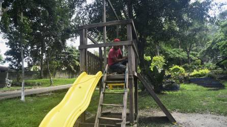 Un joven le da mantenimiento a los juegos del parque infantil como parte de los trabajos de remodelación.