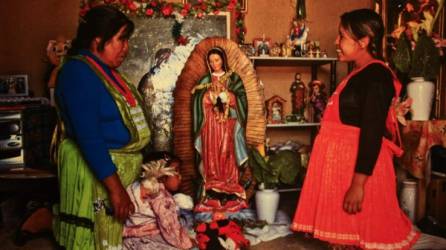 Dos mujeres indígenas frente a una imagen de la Virgen de Guadalupe. La fe es transmitida a los pequeños.