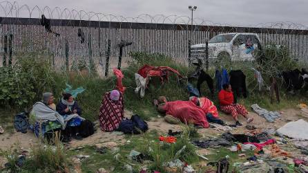 Varios migrantes permanecen a un costado del alambrado que marca la frontera con Estados Unidos pese a las bajas temperaturas.