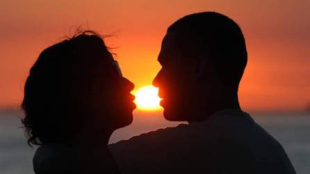 Una pareja se besa al atardecer en la playa del Arpoador en Ipanema. EFE/Marcelo Sayao/Archivo