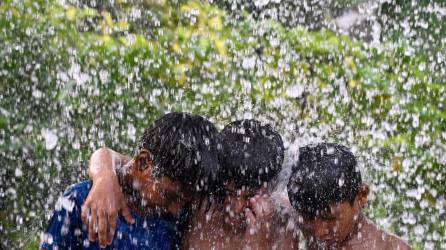 Tres menores se refrescan durante una ola de calor que golpea fuertemente a la India.